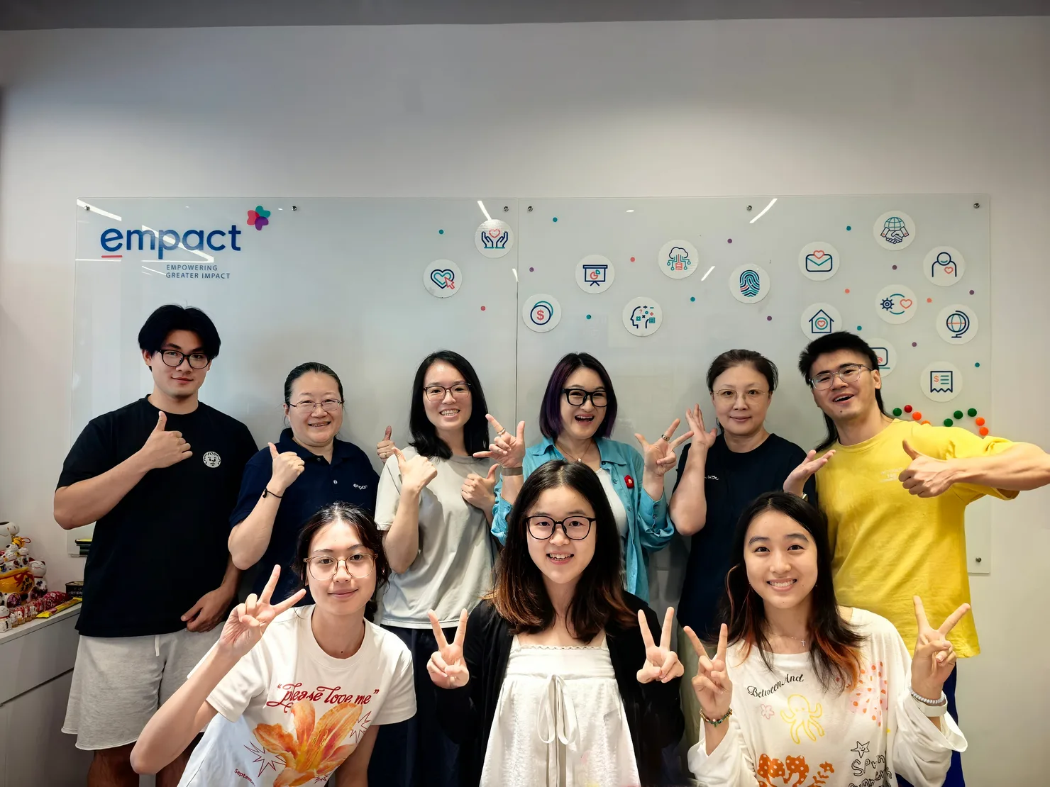 Empact 团队在办公室品牌墙前合影